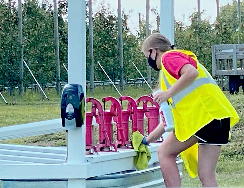 A Ferguson’s Orchards employee wiping down an attraction at the Eau Claire location. The Fergusons created special sanitizing crews in 2020, putting them in bright vests to make them clearly visible to customers. (Courtesy Andy Ferguson/Ferguson’s Orchards)
