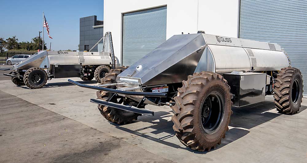 At left, the first Mini GUSS with a spray tower stands at about 75 percent of the full-size version, seen last year at the company’s headquarters and manufacturing facility in Kingsburg, California. The Mini is 6 feet wide and 19 feet long. (TJ Mullinax/Good Fruit Grower)