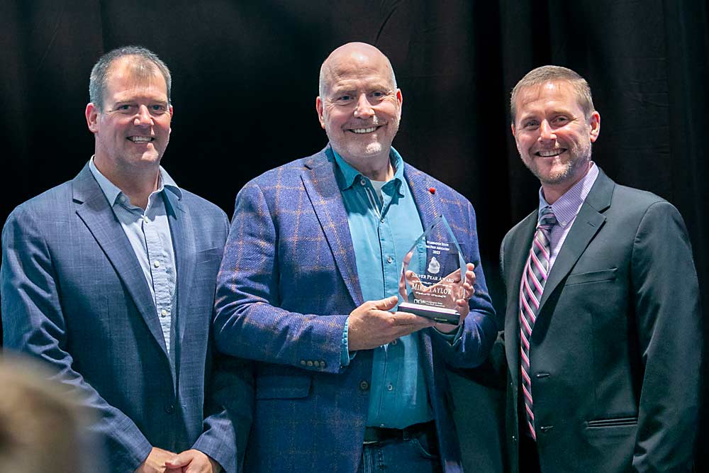 Mike Taylor, center, accepts the Silver Pear Award presented by Mark Hambelton, left, and Marty Olsen, right, saying he couldn’t be more excited about being on the forefront of the pear industry right now. (TJ Mullinax/Good Fruit Grower)