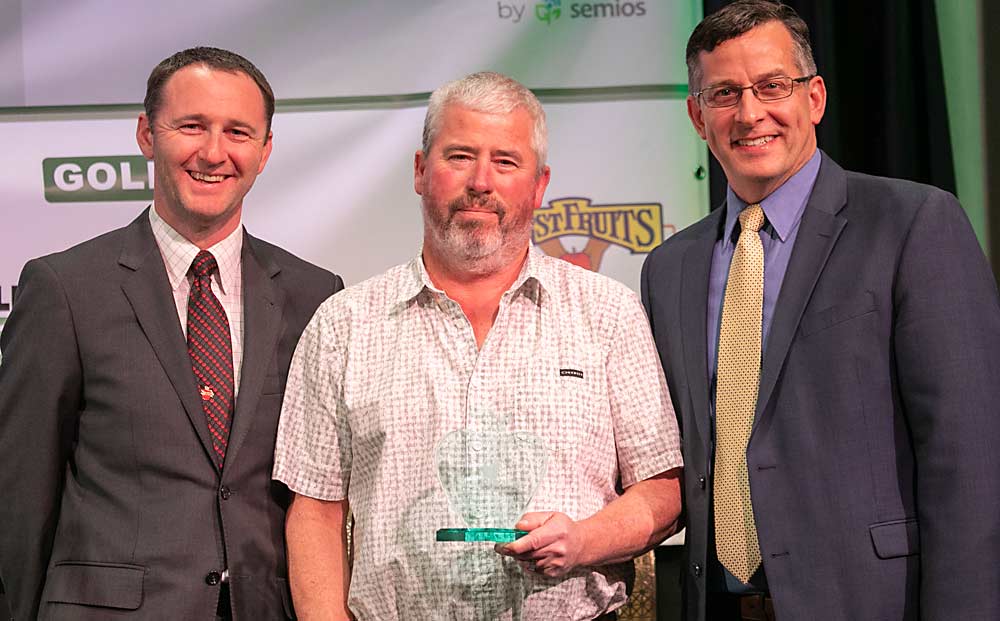 Jordan Matson, left, and Jared England, right, present the Silver Apple Award to Todd Cameron of Cameron Nursery during the Washington State Tree Fruit Association Annual Meeting on Dec. 6, 2022, in Wenatchee, Washington. (TJ Mullinax/Good Fruit Grower)