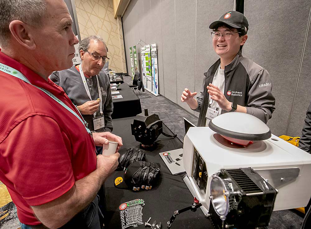 From left, David Miles and Steve Applebaum listen to Orchard Robotics CEO Charlie Wu explain his sensor technology during the International Fruit Tree Association preharvest technology workshop in Yakima, Washington, in February. Wu said the latest version of his FruitScope technology features a precision GPS sensor on top and an LED light on the side to enhance the precision of the images collected. (TJ Mullinax/Good Fruit Grower)