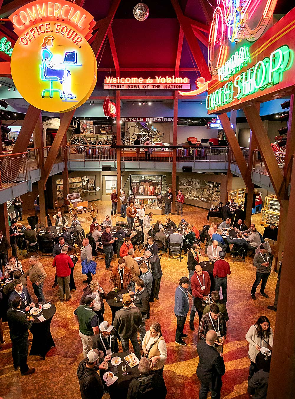 Participants of the International Fruit Tree Association orchard tour mingle under Yakima, Washington’s neon history in February at the Yakima Valley Museum after touring Yakima Valley orchards earlier in the day. (TJ Mullinax/Good Fruit Grower)