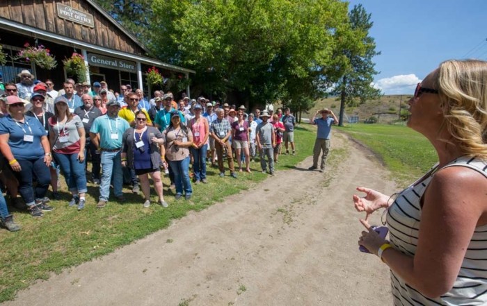The old Okanagan post office in Spallumcheen, British Columbia, was the perfect setting for 2018 International Fruit Tree Association summer tour group photo as LauraLee Heuser Gale, right, gives an announcement in the hot afternoon sun on July 24. (TJ Mullinax/Good Fruit Grower)