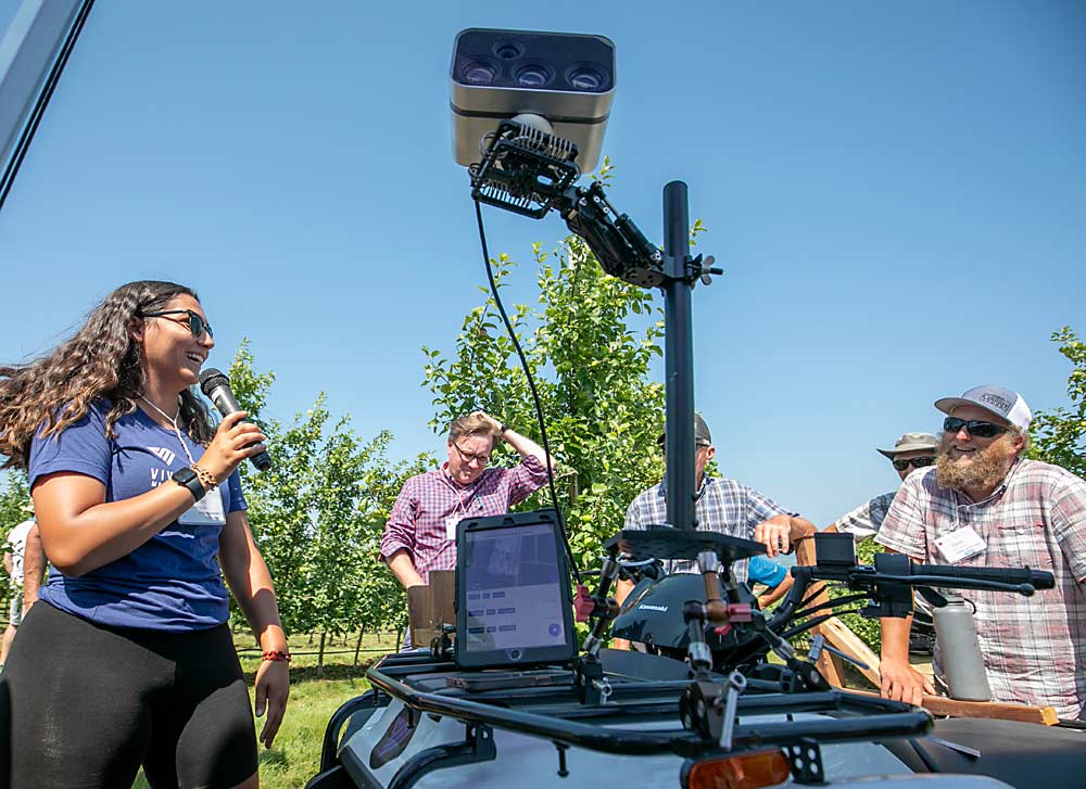 Hannah Nascimento, left, from Vivid Machines answers questions from Pavel Bourgeois, far right, about precision crop load management technology at Crisp Growers, a stop on the second day of the tour. (TJ Mullinax/Good Fruit Grower)