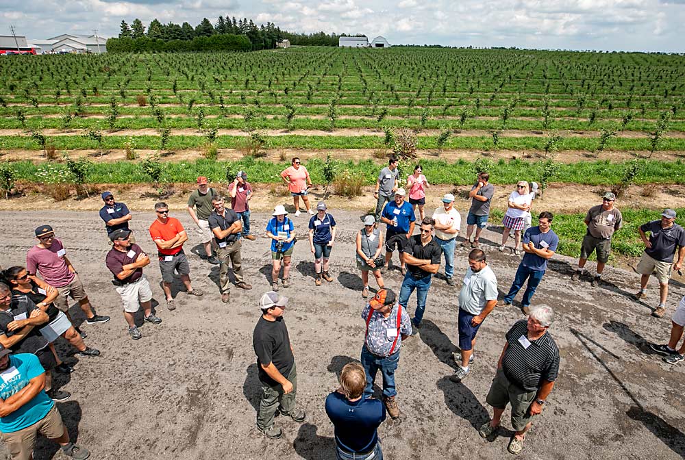 Brett Schuyler, center bottom in gray hat, speaks to members of the International Fruit Tree Association Summer Study Tour in Ontario, Canada, last July. “I can’t do anything without the people running our farm,” he said of the Caribbean farmworkers who come on seasonal visas every year. (TJ Mullinax/Good Fruit Grower)