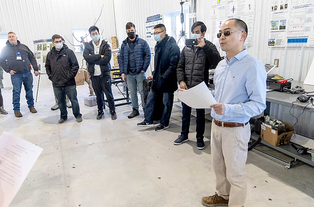 Penn State University professor Long He, right, summarizes for an IFTA audience some of the projects his ag engineering team is pursuing. Penn State built a facility at its Fruit Research and Extension Center to house the team’s engineering projects. (Matt Milkovich/Good Fruit Grower)