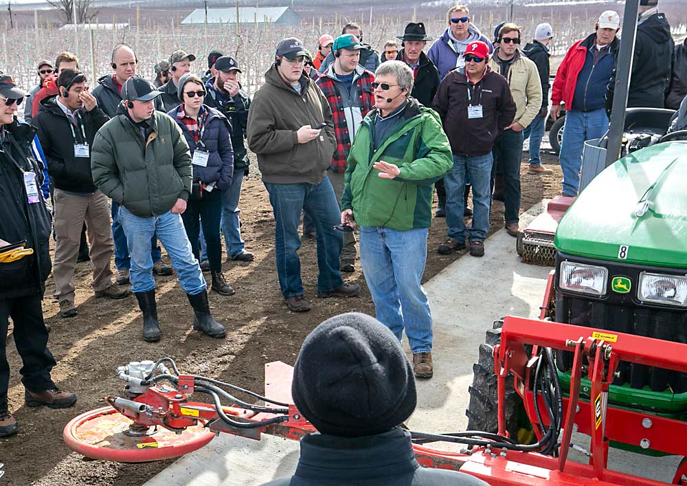 In 2017, Robinson explains his Dyna Trim mower, which he uses to mow weeds directly under trees instead of cultivating the soil. The disc bounces around tree trunks without damaging them, Robinson said. (TJ Mullinax/Good Fruit Grower)