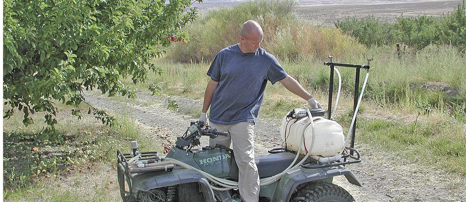 Technician Duane Larson uses an ATV to apply an ultra-low volume spray. Photo courtesy of Dr. Alan Knight