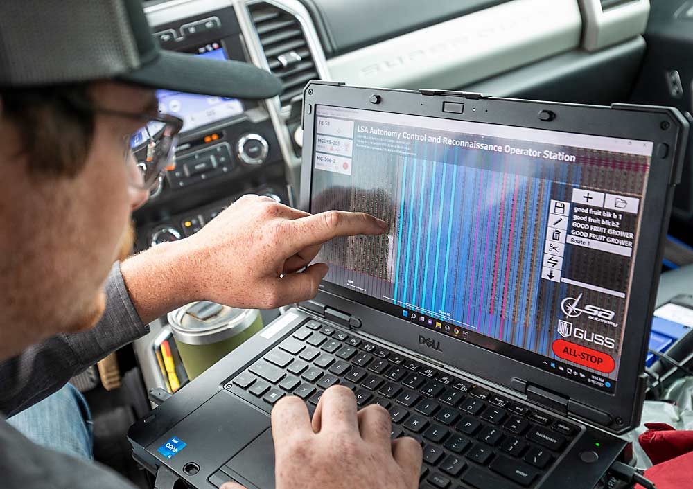 Bryan Monson controls and monitors the work of the Mini GUSS on a laptop from his pickup during the June demonstration. “My goal is to run this from Italy,” he said. (TJ Mullinax/Good Fruit Grower)