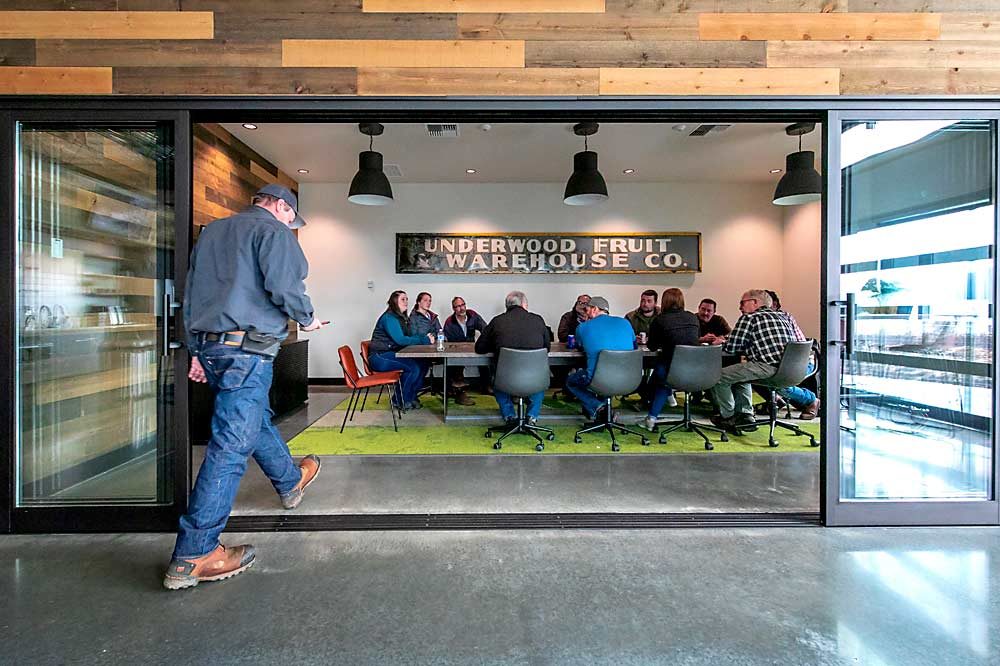 Employees gather in a boardroom under an old Underwood Fruit sign salvaged from the burned building. (TJ Mullinax/Good Fruit Grower)