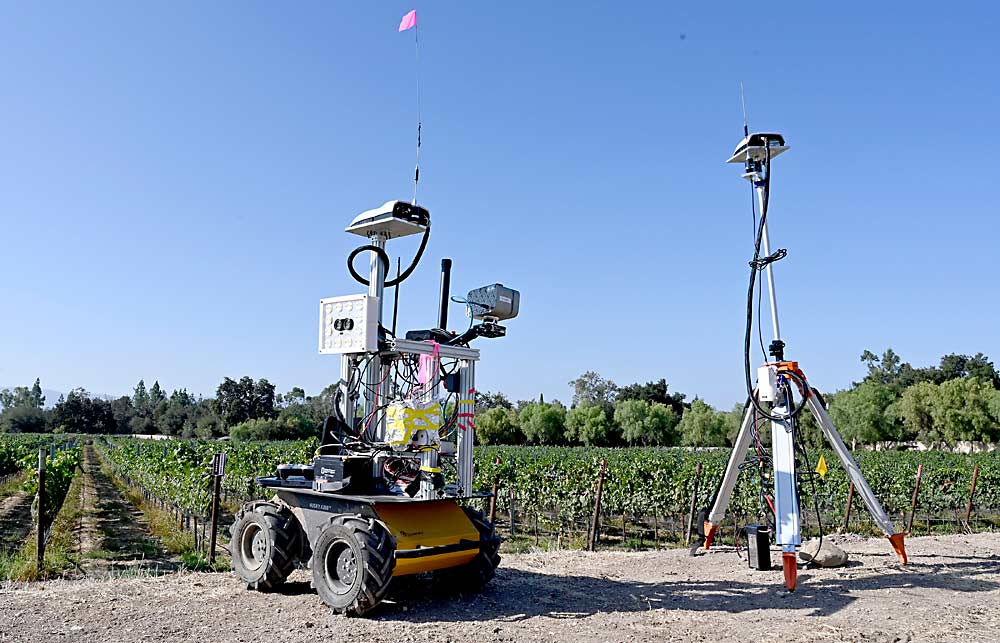 A Cornell-designed PhytoPatholoBot (PPB), left, parked next to a California vineyard. The device on the right is a real-time kinematic positioning station, which provides correction to increase accuracy of the GPS unit on the bot. Since last year, Cornell researchers have collaborated with NASA to combine satellite data with on-the-ground vineyard assessments from the PPB. (Courtesy Leo Liu/Cornell University)