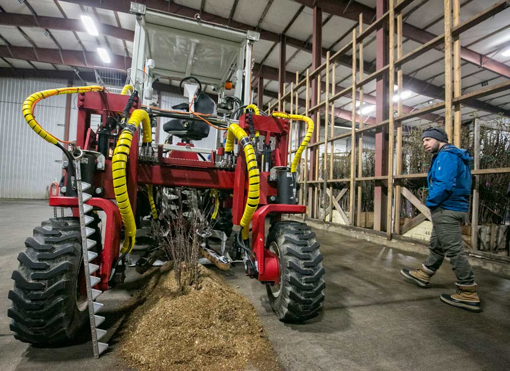 TJ Mullinax/Good Fruit Grower Roger Mennell looks over one of Willow Drive Nursery’s custom-made machines for automating some tasks during the 2017 International Fruit Tree Association 60th annual conference in February. This machine digs and cuts rootstocks from rows and deposits them into bins located at the back of the machine for use at Willow Drive’s Ephrata, Washington, nursery. (TJ Mullinax/Good Fruit Grower)