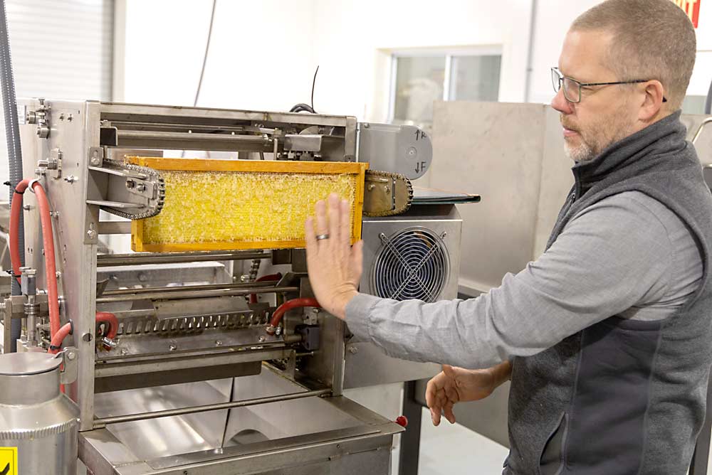 Wyns displays honey extraction machinery. The “uncapper” removes wax cappings from a beehive rack so the extractor can spin honey out of the combs. (Matt Milkovich/Good Fruit Grower)