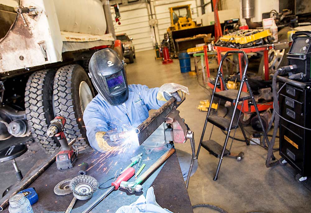 Victor Gonzalez welds a truck mud flap in the shop. The labor management app his employers use automatically directs hours and costs for this work to the correct business unit. (Ross Courtney/Good Fruit Grower)