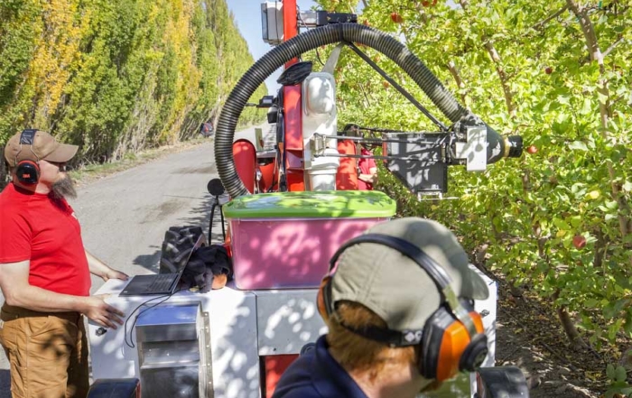 Operators of an Abundant Robotics automated vacuum harvester monitor the test vehicle working a Fuji apple block during the 2016 Washington apple harvest. (TJ Mullinax/Good Fruit Grower)