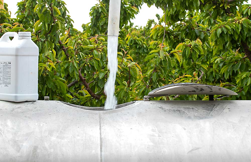 Inputs are up for cherry production in 2022, including the costs for chemicals in the sprayer and wages for the operator driving it. Here, water fills a spray fan in a Yakima, Washington-area cherry orchard in early June. (TJ Mullinax/Good Fruit Grower photo illustration)