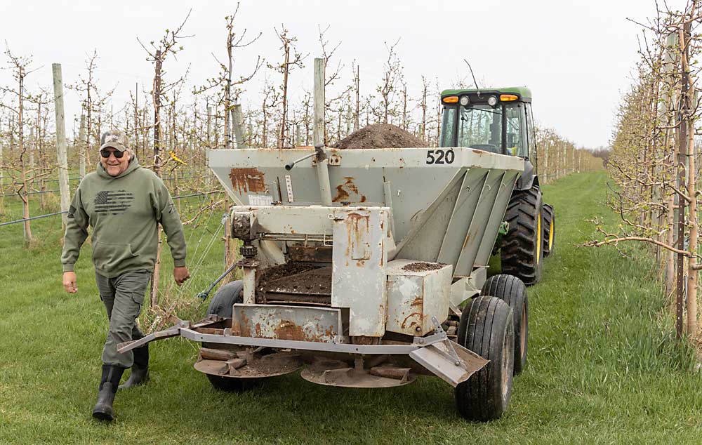 Tom Rasch Jr. takes a break from spreading chicken-manure-based fertilizer in his orchard blocks in April. He was initially skeptical of his son’s desire to convert the family orchard to organic, but he now embraces the challenge — and the higher prices organic apples fetch. (Matt Milkovich/Good Fruit Grower)