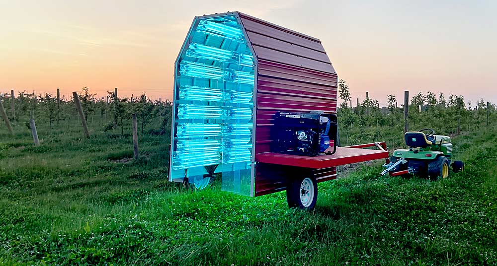 Pulled by a lawnmower and powered by an attached generator, a unit designed by Cornell University researchers applies anti-microbial UV-C light to control fire blight in orchards. Two years of trials show that UV-C can be an effective alternative to fungicides and antibiotics. (Courtesy Kerik Cox/Cornell University)