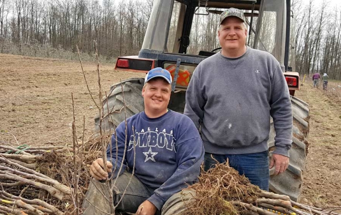 Twin Bee Orchard co-owner Tony Blattner and his son Nathan, left, take a break while planting 4,600 Smitten trees in spring 2016. Twin Bee, in west-central Michigan, has 135 acres of apples, including Gala, Red Delicious, Fuji, Honeycrisp, McIntosh, Empire, Ida Red and Jonagolds. (Courtesy Twin Bee Orchard LLC.)