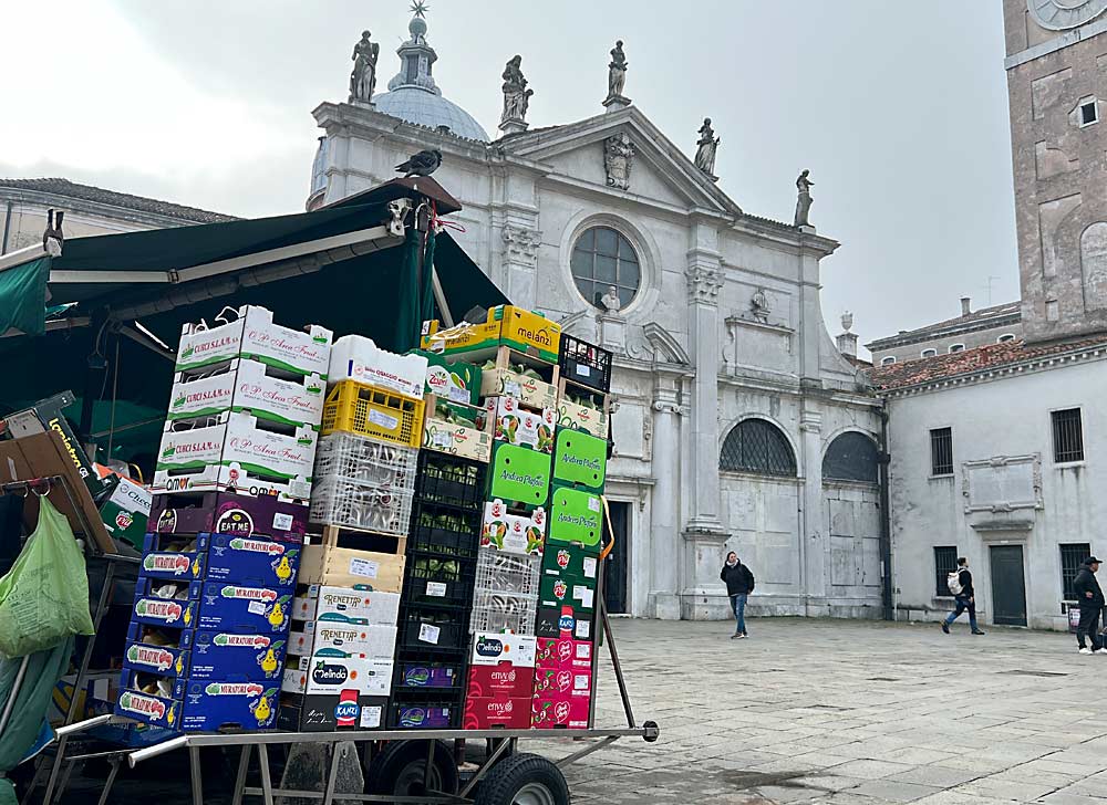 Branded apples, including Kanzi, Envy and Pink Lady, await restocking alongside traditional varieties at a produce stand outside a historic church in Venice, Italy. (Ross Courtney/Good Fruit Grower)