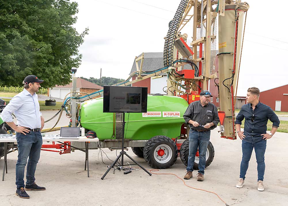 Munckhof representatives Han Smits, left, and Vincent Sanders, far right, discuss precision orchard collaboration at Wittenbach Orchards in Belding, Michigan, in July. Between them is Ross Gansz, vice president of LaGasse Machine & Fabrication, Munckhof’s U.S. distributor. (Matt Milkovich/Good Fruit Grower)