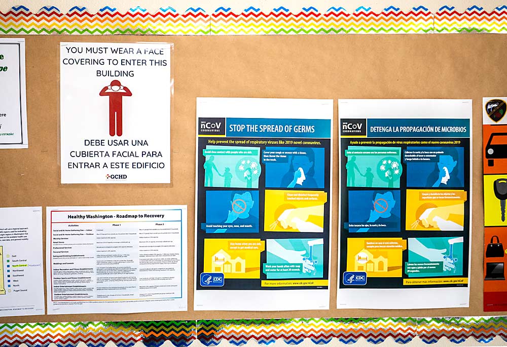 Signs explaining rules regarding the coronavirus fill a bulletin board in February at a Washington Growers League temporary farmworker housing facility in Mattawa, Washington. Vaccines are on the way, but until then, growers and housing operators are gearing up for another fruit season under pandemic restrictions. (TJ Mullinax/Good Fruit Grower)