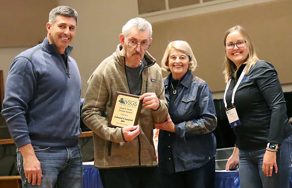Edward Crawford accepts the Lloyd H. Porter Grower of the Year award with his son, Scott, left, and his wife, Janet, right, and Washington State Grape Society President Catherine Jones, far right at the society’s annual meeting on Nov. 18, 2021. (Kate Prengaman/Good Fruit Grower)