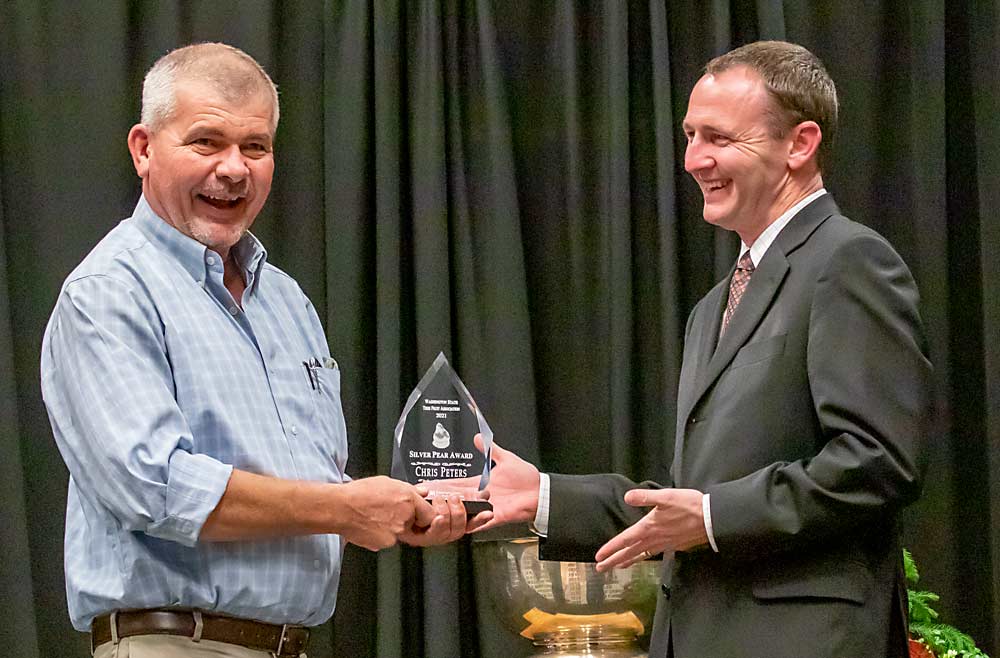 Chris Peters, left, is presented with the 2021 Silver Pear Award by Jordan Matson during the Washington State Tree Fruit Association's awards banquet on Tuesday, Dec. 7, at the Yakima Convention Center in Yakima, Washington. (TJ Mullinax/Good Fruit Grower)
