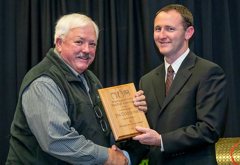 Jim Doornick, left, is presented with the 2021 Distinguished Service Award by Jordan Matson during the Washington State Tree Fruit Association's awards banquet on Tuesday, Dec. 7, at the Yakima Convention Center in Yakima, Washington. (TJ Mullinax/Good Fruit Grower)