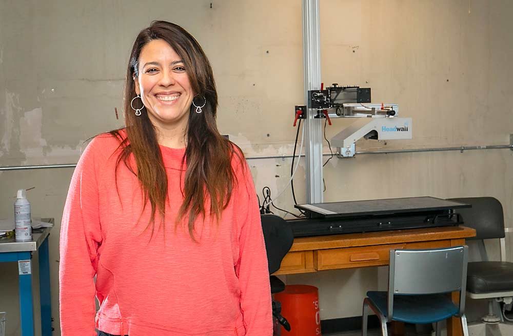 Postharvest physiologist Carolina Torres poses in front of her new hyperspectral imaging equipment at the Washington State University Tree Fruit Research and Extension Center in Wenatchee in November. She intends to use the equipment to develop an optical sorting technique to detect sun damage that’s invisible to the naked eye but puts fruit at risk of developing sunscald in storage. (TJ Mullinax/Good Fruit Grower)