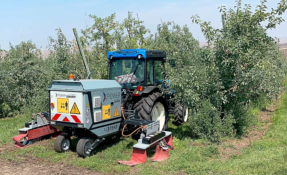 A Zasso electric weeder in an apple orchard near Quincy, Washington, last August. Burrows Tractor has tested the weeder, which kills weeds with electrical currents, in apples and hops. Oregon State University researchers are trialing the machine in blueberries. (Courtesy TJ Lange/Burrows Tractor)
